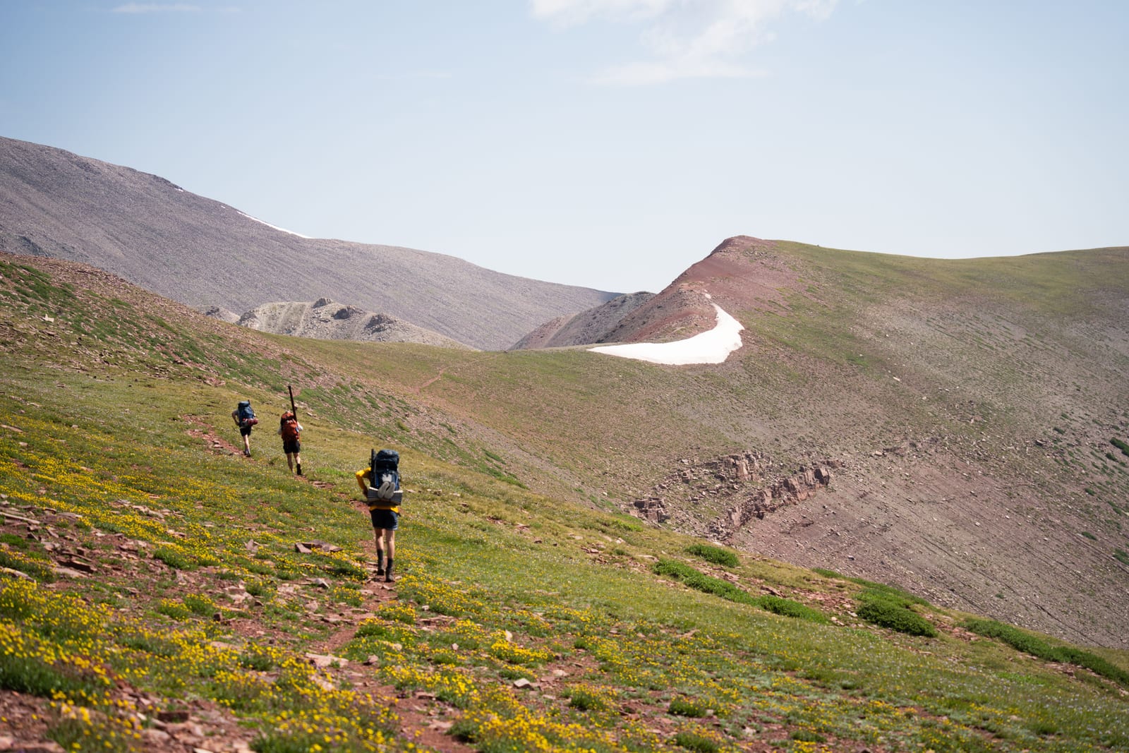 A group of hikers with packs on a mountain trail.